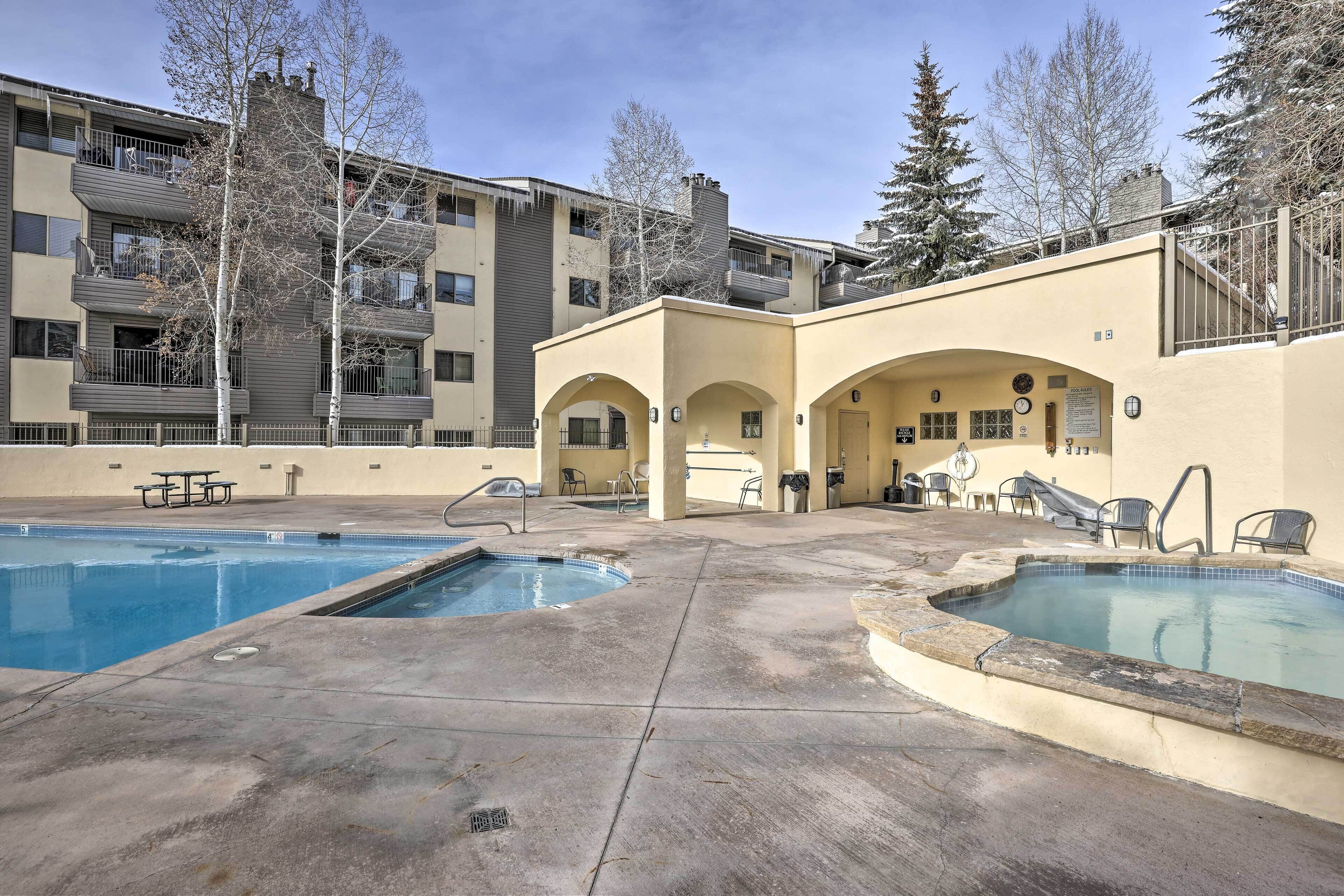 A pool area with two pools, outdoor seating, and a building with balconies.