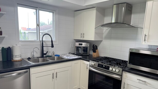 A modern kitchen with white cabinets, stainless steel appliances, and a window providing natural light. - Close to Notre Dame Family And Pet Friendly  house Heat AC  

Located in Elkhart (Elkhart)