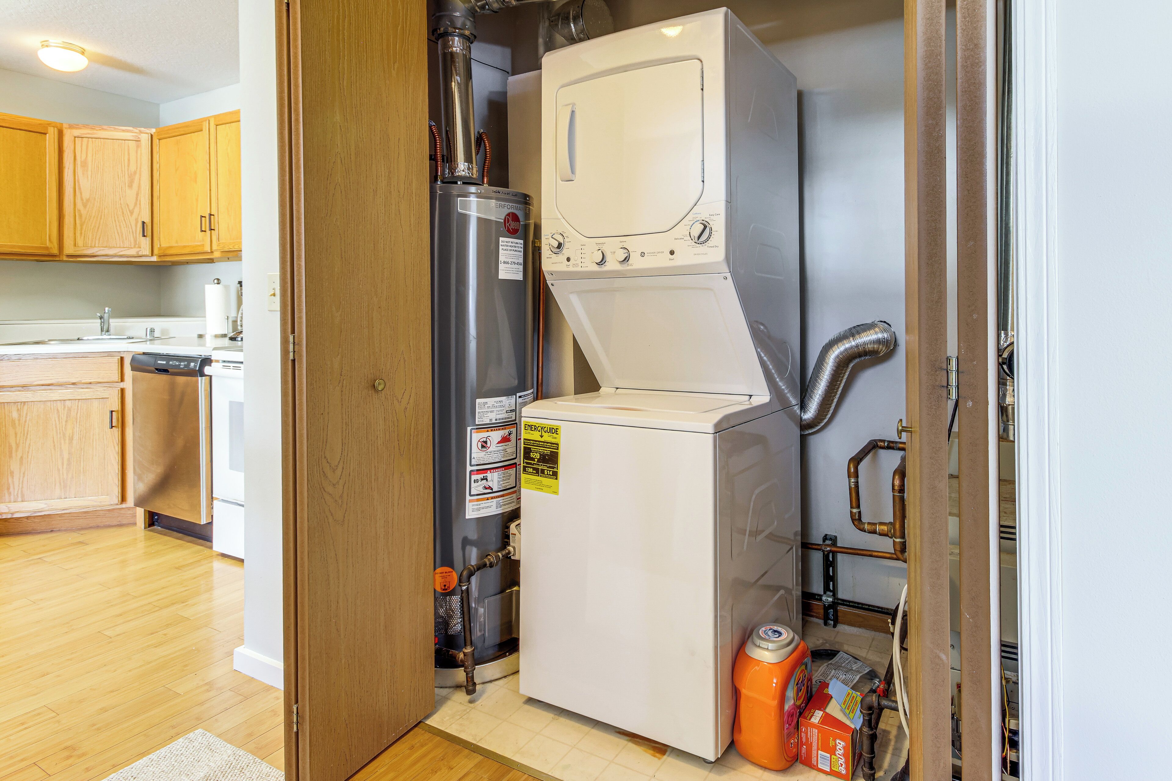 A compact laundry room with a washer and dryer, a water heater, and visible plumbing.