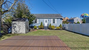 A residential house with a wooden deck, a small shed, and a fenced yard.