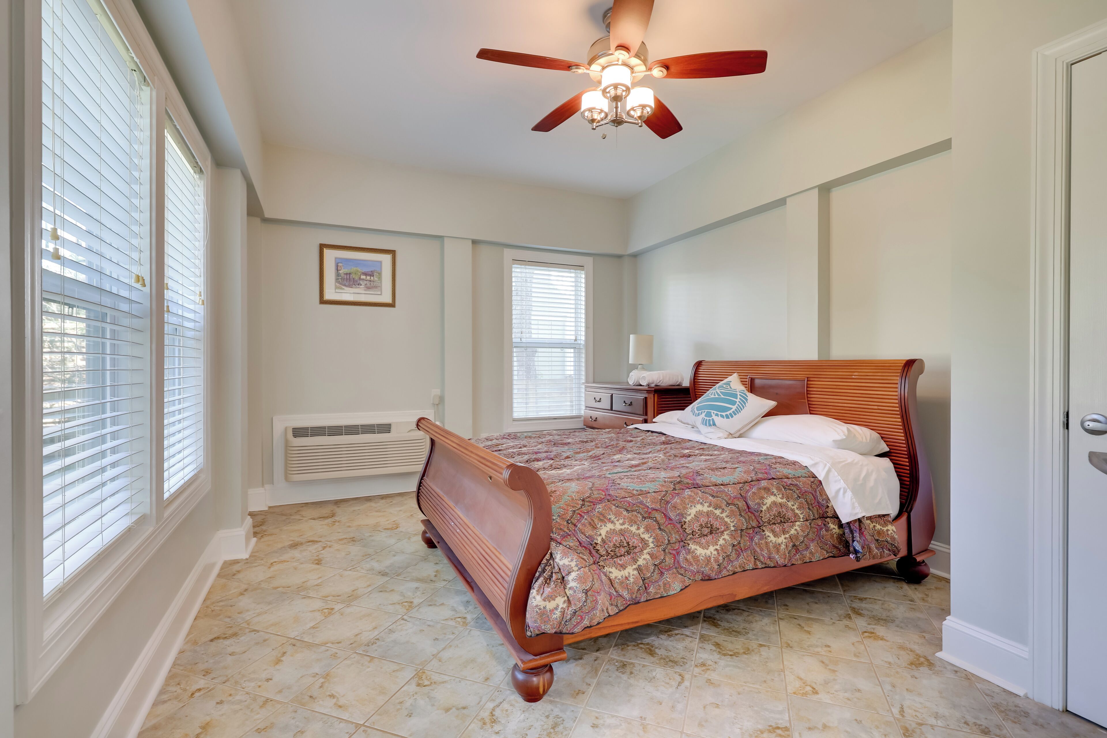 A bedroom with a wooden bed, a ceiling fan, and a radiator.