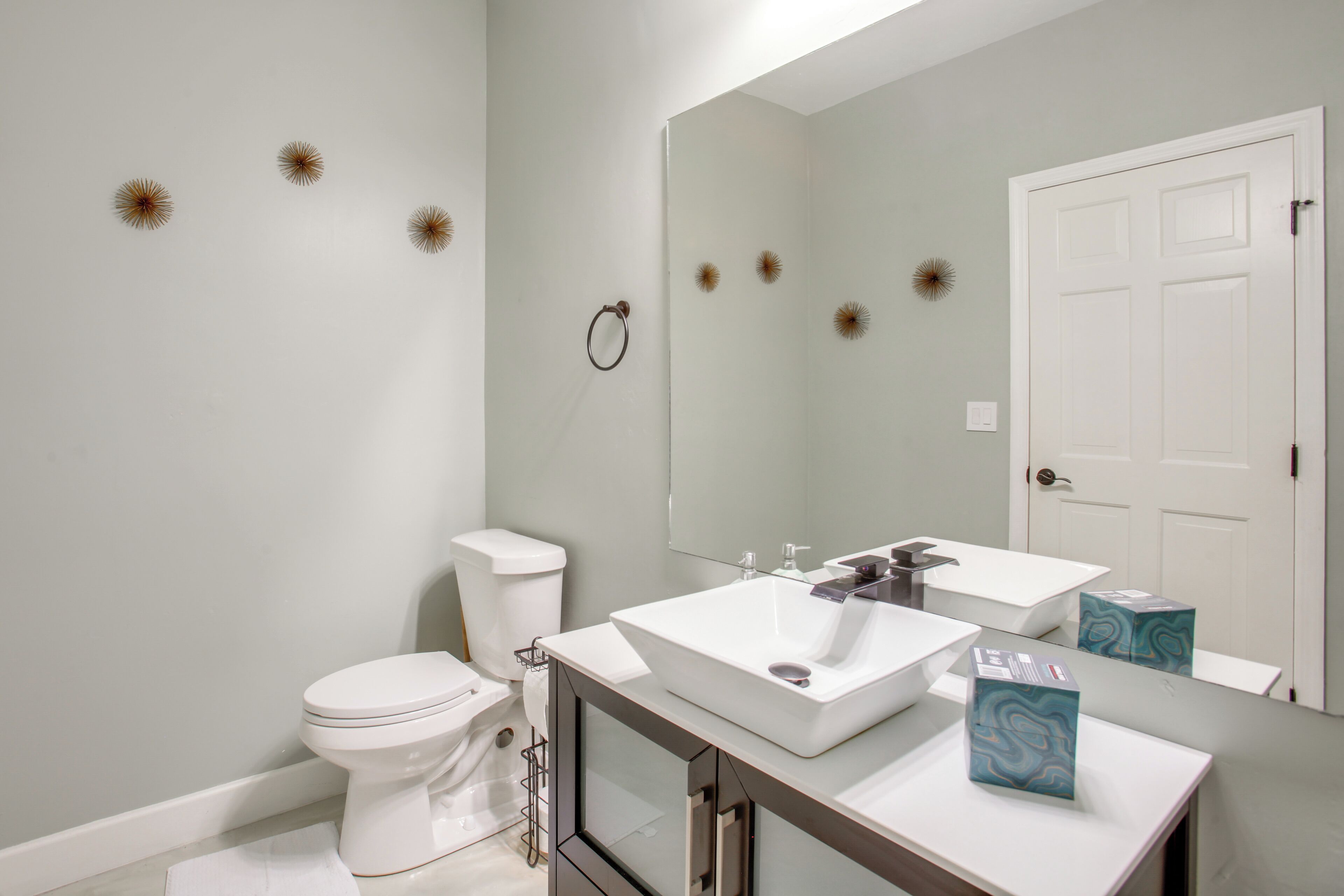 A modern bathroom with a toilet, sink, and mirror.