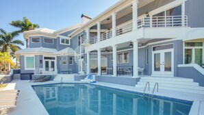 A two-story house with a swimming pool, outdoor seating, and a covered patio area. - Riverfront Fort Myers Luxury Home w/ Heated Pool! (Fort Myers)