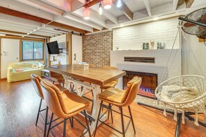 A modern kitchen with a wooden table and bar stools, a brick wall, and a fireplace. - Hot Tub, Trails & Tranquil Views! Cozy Seatac Spot (Seattle)