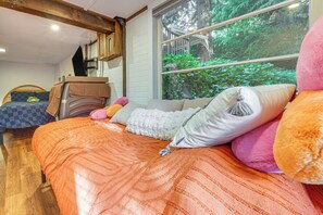 A bedroom with a large bed, a window with a view of greenery, and a wooden ceiling. - Hot Tub, Trails & Tranquil Views! Cozy Seatac Spot (Seattle)