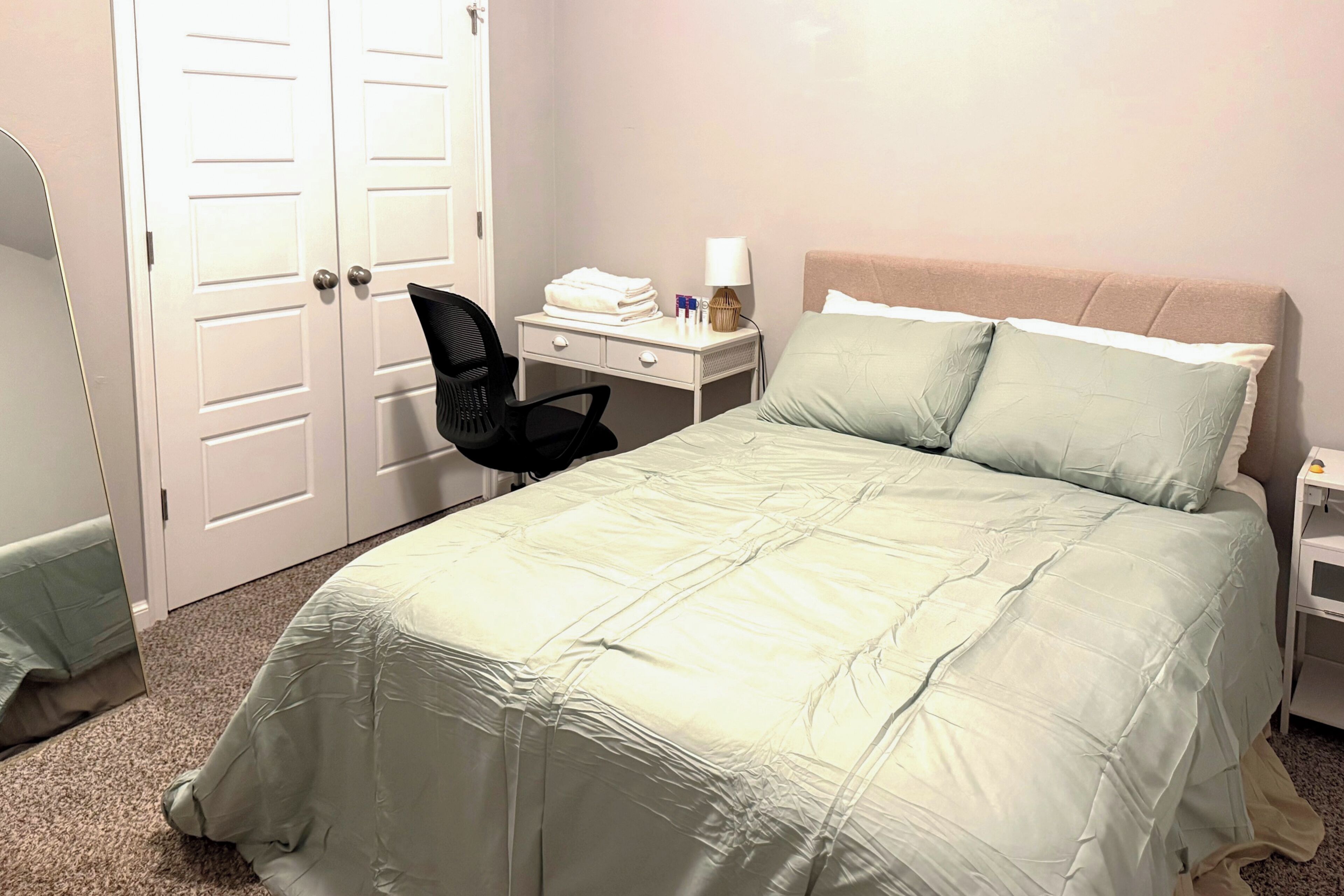 A hotel room with a bed, a nightstand, a chair, and a wardrobe.