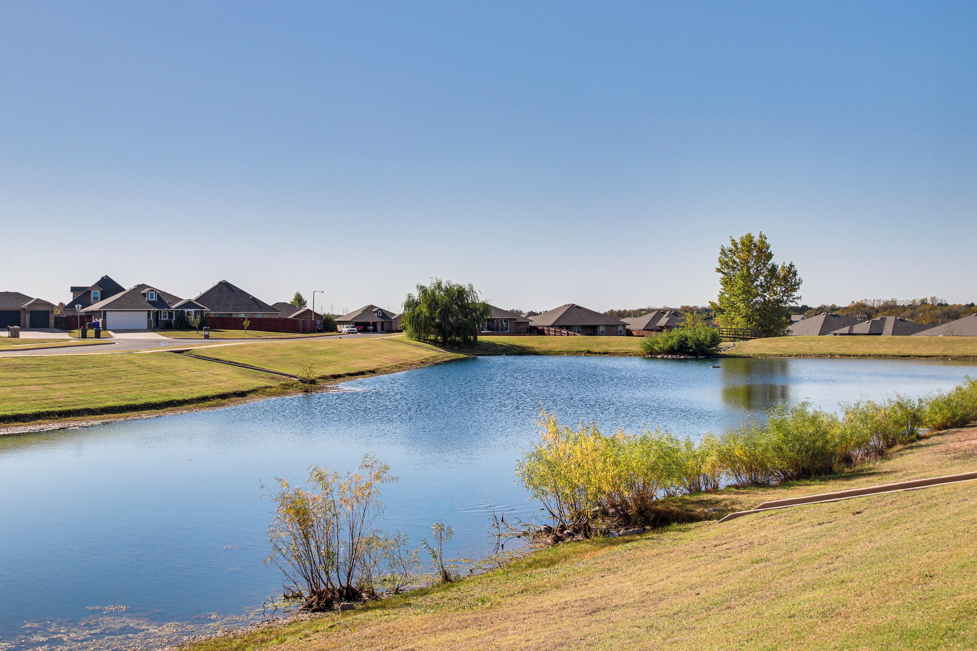 A residential area with houses, a pond, and a clear sky.