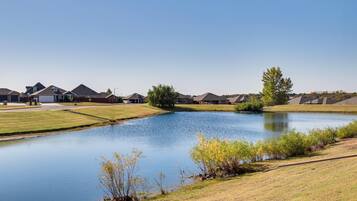 A residential area with houses, a pond, and a clear sky.