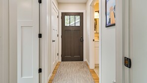 A hallway with a wooden floor, a brown door, and white walls. - Fish, Swim & Explore! 2-cabin Camp on Round Lake (Luck)