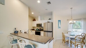 A kitchen with a central island, bar stools, a dining table with chairs, and a view of the outdoors through a window. - Family Haven w/ Pool! 8 Mi to Warm Mineral Springs (North Port)