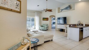A modern living room with a white sofa, a dining area with a kitchen island, and a ceiling fan. - Family Haven w/ Pool! 8 Mi to Warm Mineral Springs (North Port)