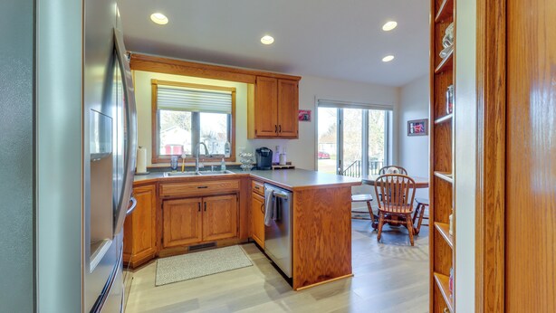 A modern kitchen with wooden cabinets, a stainless steel refrigerator, a built-in oven, and a large island with a sink. - Work & Play: Pet-friendly Fargo Home 6 Mi to Dtwn (Fargo)