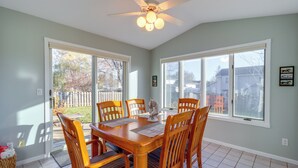 A dining area with a wooden table and chairs, a ceiling fan, and large windows with a view of the outside. - Work & Play: Pet-friendly Fargo Home 6 Mi to Dtwn (Fargo)