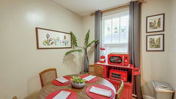 A dining area with a wooden table, red placemats, and a red appliance unit.