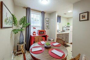 A compact kitchen with a dining area, featuring a red microwave, a sink, and a window with curtains. - < 1 Mi to Dtwn Texarkana: Couple's Retreat w/ Yard (Texarkana)