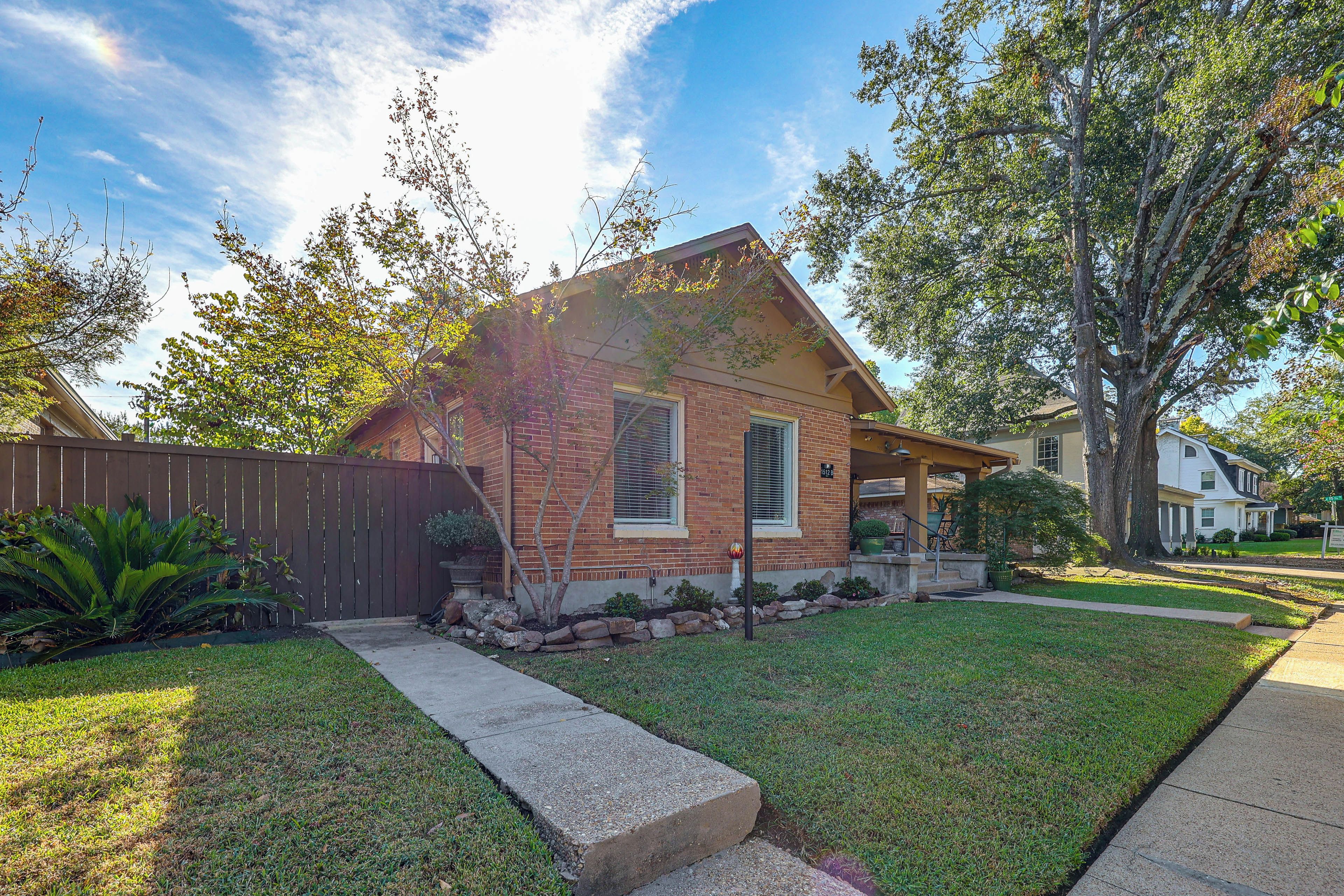 A residential house with a brick exterior, a front porch, and a well-maintained lawn.