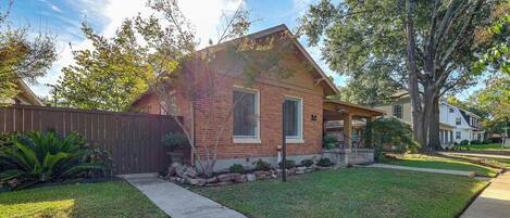 A residential house with a brick exterior, a front porch, and a well-maintained lawn.