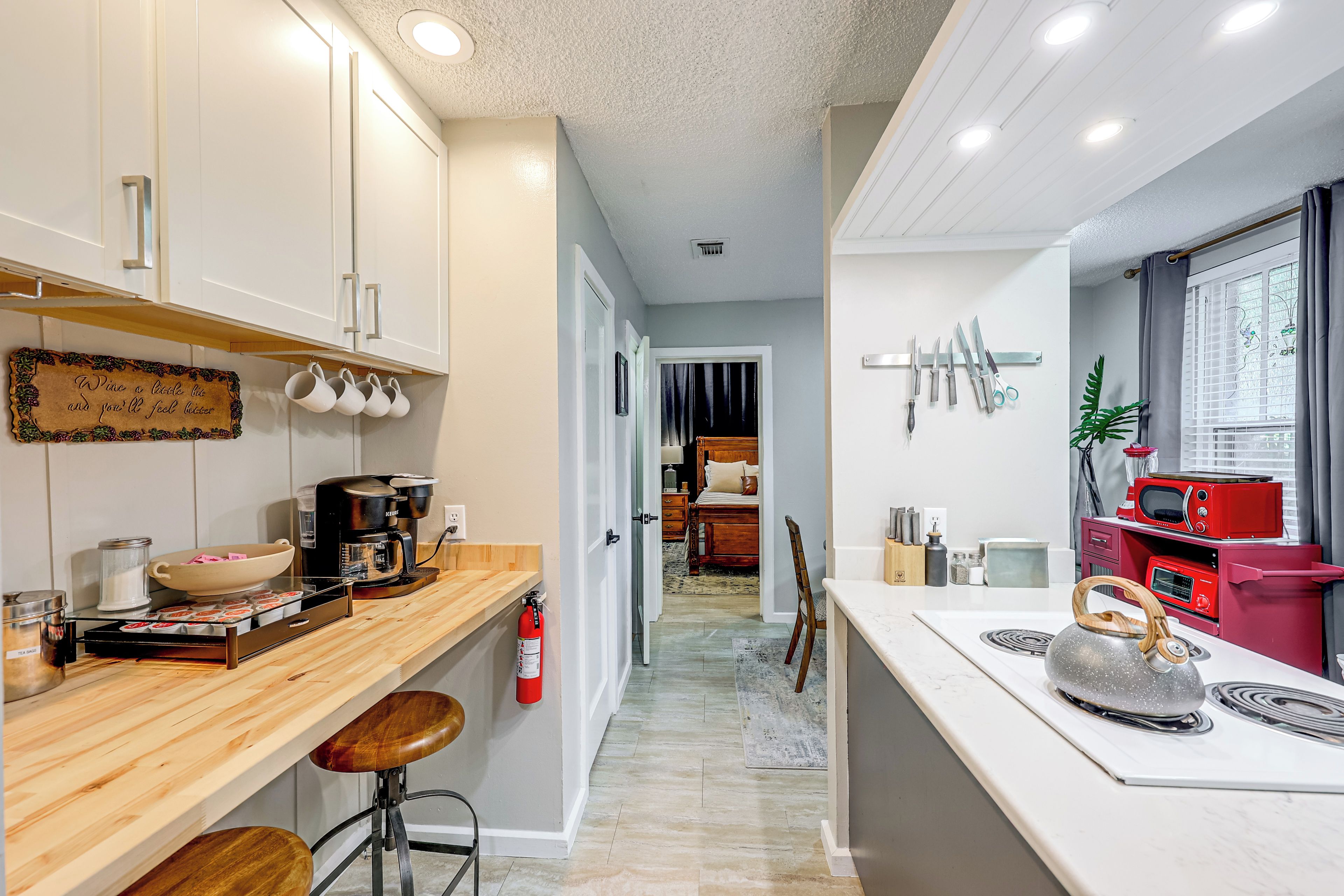 A modern kitchen with a wooden countertop, a coffee machine, and a red microwave.