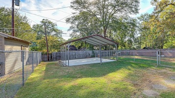 A fenced backyard with a covered patio area, a wooden fence, and a utility pole.