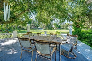 An outdoor patio with a table and chairs, surrounded by lush greenery and a view of a lawn and trees. - Explore Dtwn Sarasota & Beaches: Home w/ Lush Yard (Sarasota)