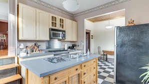 A kitchen with wooden cabinets, a stainless steel sink, and a black refrigerator. - Pet-friendly Historic Library Home on Route 66 (Virden)