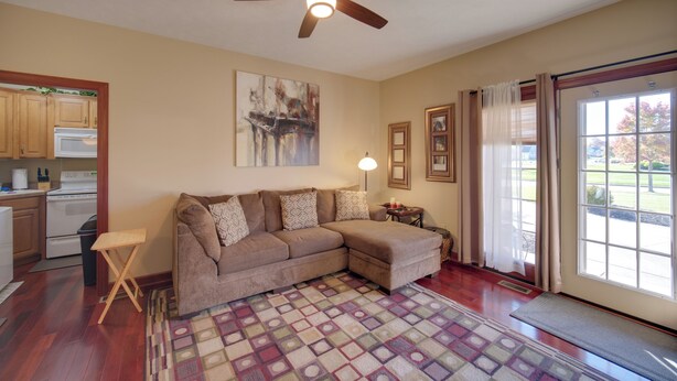 A living room with a sectional sofa, a ceiling fan, a rug, and a large window with curtains. - Convenient Apt 2 Mi to North Chagrin Hiking! (Highland Heights)