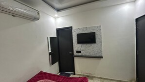 A small room with a closed door, a mounted TV, and a marble-patterned wall. - R.K Hotel & Restaurant (Khatoo)