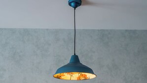 Ein Esstisch mit blauer Tischdecke, gelben Stühlen und einer blauen Pendelleuchte.