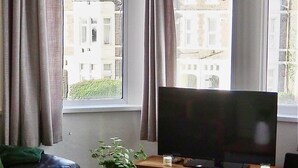 Un soggiorno con televisore su un mobile in legno, un tavolino con una pianta e due divani in pelle nera.