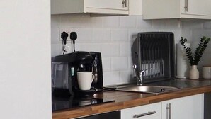 Una cucina moderna con mobili bianchi, una macchina da caffè nera, un tostapane e un lavello.
