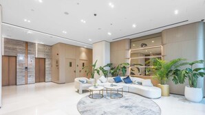 Eine moderne Lobby mit einem weißen Sofa, zwei Couchtischen und Topfpflanzen.