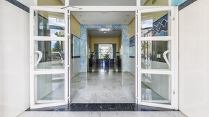 Un vestíbulo de hotel con piso de mármol y puertas de vidrio que dan al área de recepción.