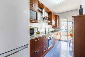 A modern kitchen with wooden cabinets, a built-in microwave, and a stove. - A&N Algarrobo Beach 6 (Algarrobo Costa)