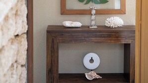 A bathroom with a wooden vanity, a framed leaf artwork, a towel, and a decorative shell. - THE GARDEN Bise (Motobu)