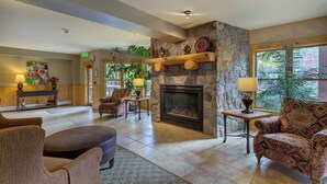 A spacious lobby with a stone fireplace, comfortable seating, and a large window offering a view of greenery. - Walk to the Lifts! Cozy Condo with Access to Outdoor Hot Tubs (Keystone)