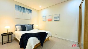 Un dormitorio con cama, mesitas de noche y decoración en la pared.