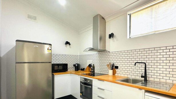 Una cocina compacta con refrigerador de acero inoxidable, microondas, estufa y pileta.