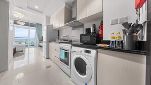 Une cuisine moderne équipée d’un lave-linge et d’un sèche-linge intégrés, d’une machine à café et offrant une vue sur l’extérieur.