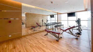 Une salle de sport moderne dotée d’un plancher en bois, d’équipements d’exercice et de grandes fenêtres.