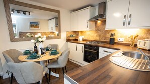 A modern kitchen with white cabinets, a wooden countertop, and a built-in stove. - Rose Cottage - 2 Bedroom Cottage - Penally (Tenby)