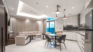 A modern kitchen with a built-in oven, a dining area with a round table and chairs, and a seating area with a sofa and chairs. - Stayshort - 1 Bed in Business Bay Sleeps 2 With City Views (Dubai)