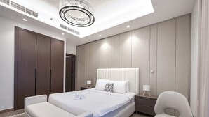 A modern hotel room with a large bed, a separate sofa, a small table, and a chair. - Stayshort - 1 Bed in Business Bay Sleeps 2 With City Views (Dubai)
