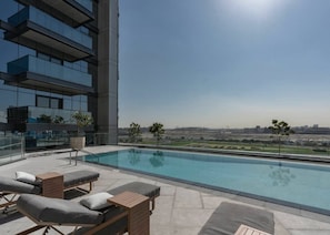 A rooftop pool with lounge chairs and a view of a cityscape. - Stayshort - 1 Bed in Business Bay Sleeps 2 With City Views (Dubai)