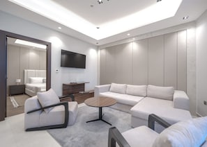 A modern living room with a sofa, armchairs, a coffee table, and a TV mounted on the wall. - Stayshort - 1 Bed in Business Bay Sleeps 2 With City Views (Dubai)