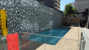 Una piscina amb una barrera de vidre i un senyal vermell amb les normes d'ús.