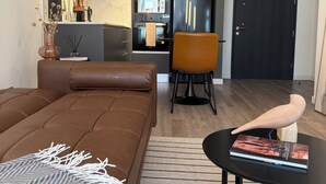 Un saló modern amb un sofà marró, una taula de cafè negra i una catifes a ratlles.