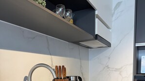 Una cuina moderna amb un rentaplat de superfície inoxidable, una cafetera i un suport de ganivets.