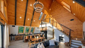 Un loft espacioso con techo alto, vigas de madera, zona de comedor, sala de estar con sofá y escalera.