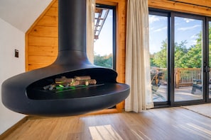 Ein modernes Interieur mit Kaminofen, Holzwänden und einer Glastür zu einer Terrasse.
