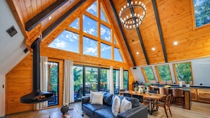 Un loft espacioso con techo alto, ventanas amplias, chimenea, comedor y cocina.